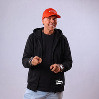 Redo trägt den Bubensahne Zipper offen über einem schwarzen Shirt
